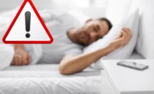 uomo con cellulare sul comodino e segno attenzione