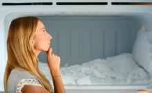 donna che guarda congelatore con ghiaccio